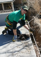 Brian of Denver Gutter Cleaning scooping debris out of a gutter