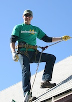 Brian Flechsig Owner Operator of Denver Gutter Cleaning wearing a harness roped off on a roof  