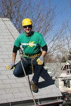 Brian Flechsig of Denver Gutter Cleaning wearing a harness and helmet roped off on a roof